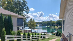 Une propriété située au bord d’un lac, avec une clôture blanche, un chemin pavé et une vue sur le lac.