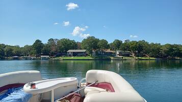 A lake view with boats docked, a clear sky, and houses in the background.