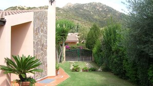 Un giardino curato con un muro in pietra, piante in vaso e vista su una montagna sullo sfondo.