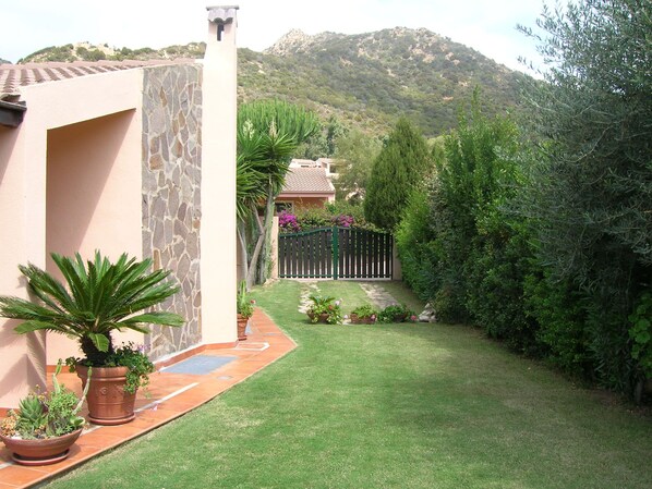 Un jardin bien entretenu, avec un mur en pierre, des plantes en pot et une vue sur une montagne en arrière-plan.