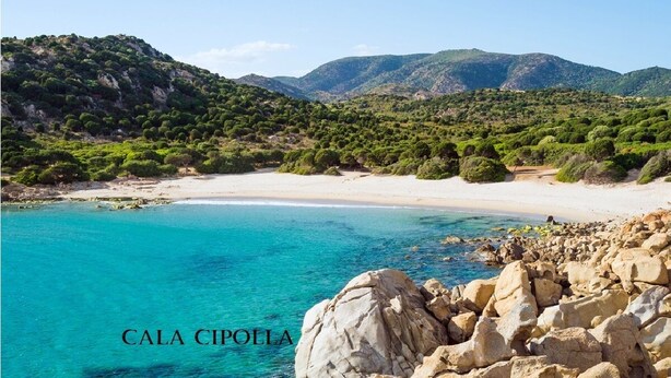 Paesaggio costiero con spiaggia, costa rocciosa e colline verdi.