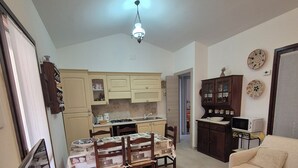 Un ambiente compatto con angolo ristoro, angolo cottura e divano.