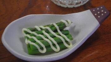 A white ceramic spoon with a purple handle containing green vegetables and a white sauce.
