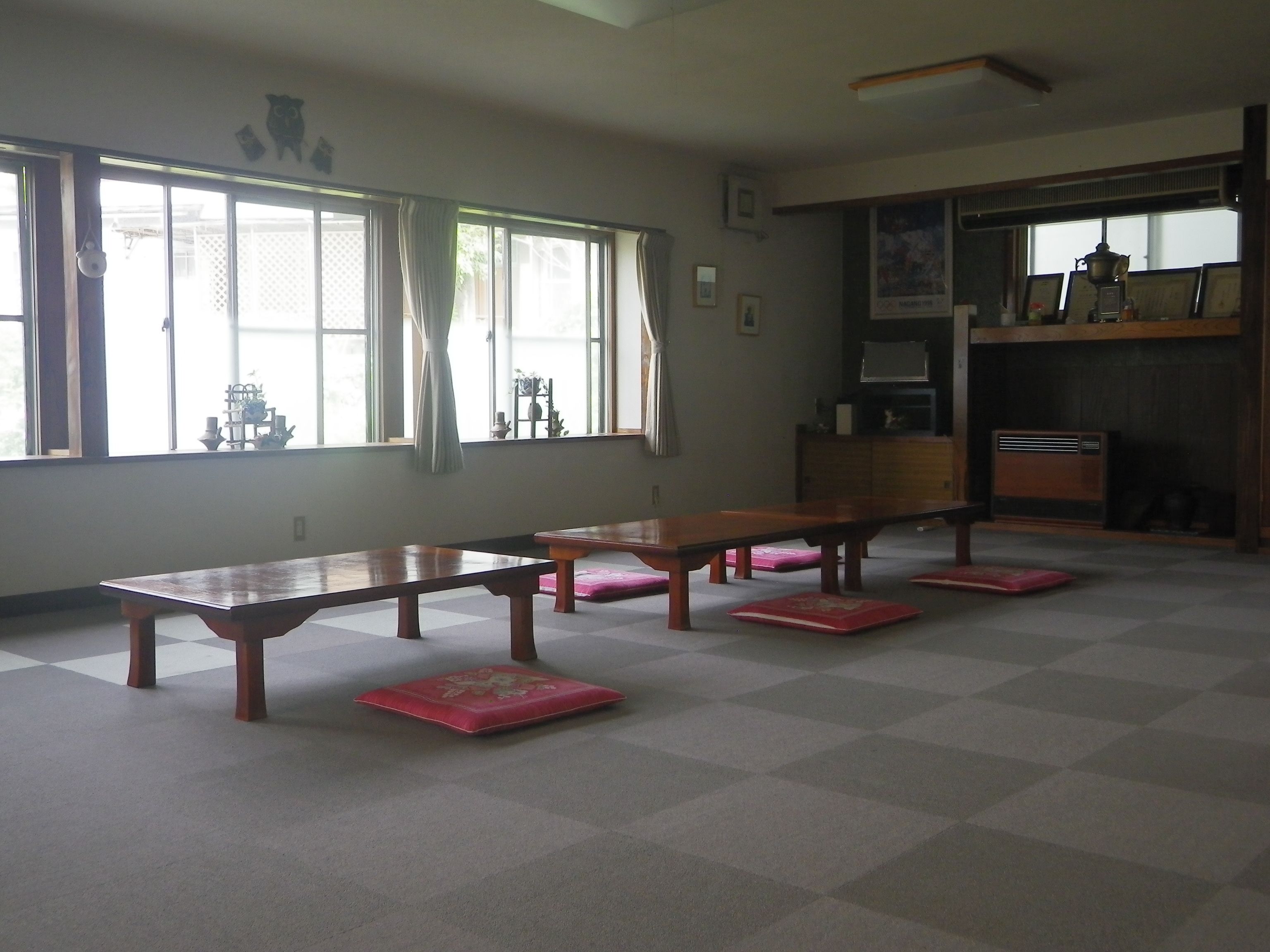A room with a long wooden table, several benches, and a radiator.