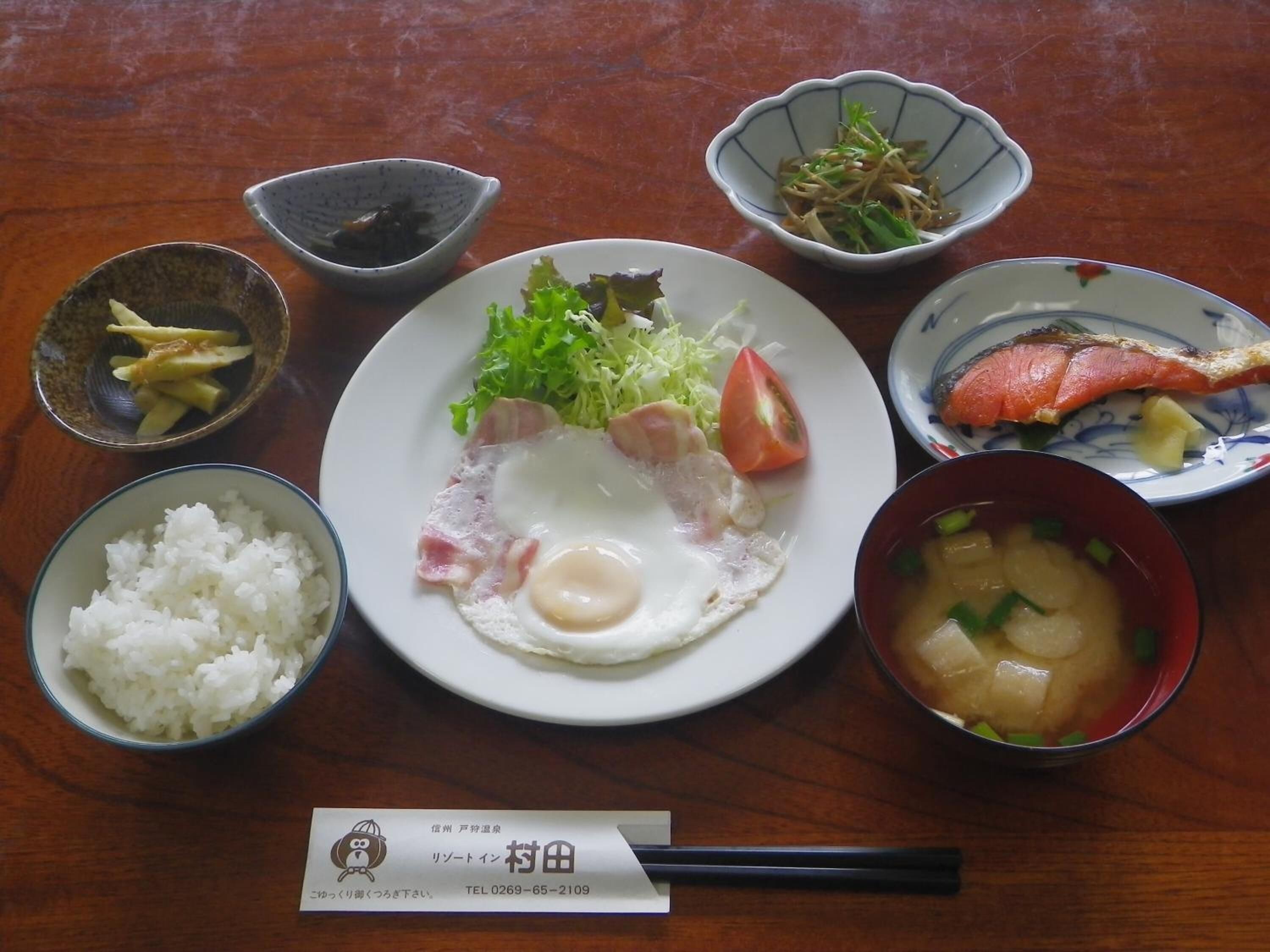 A meal with rice, egg, fish, and soup on a wooden table.