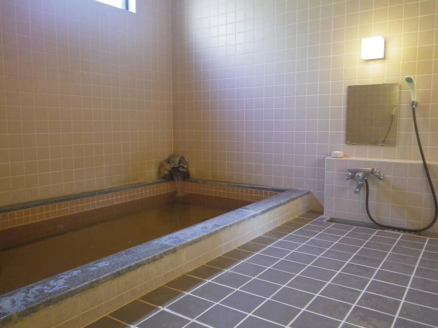 A bathroom with a bathtub, a shower, and tiled walls.