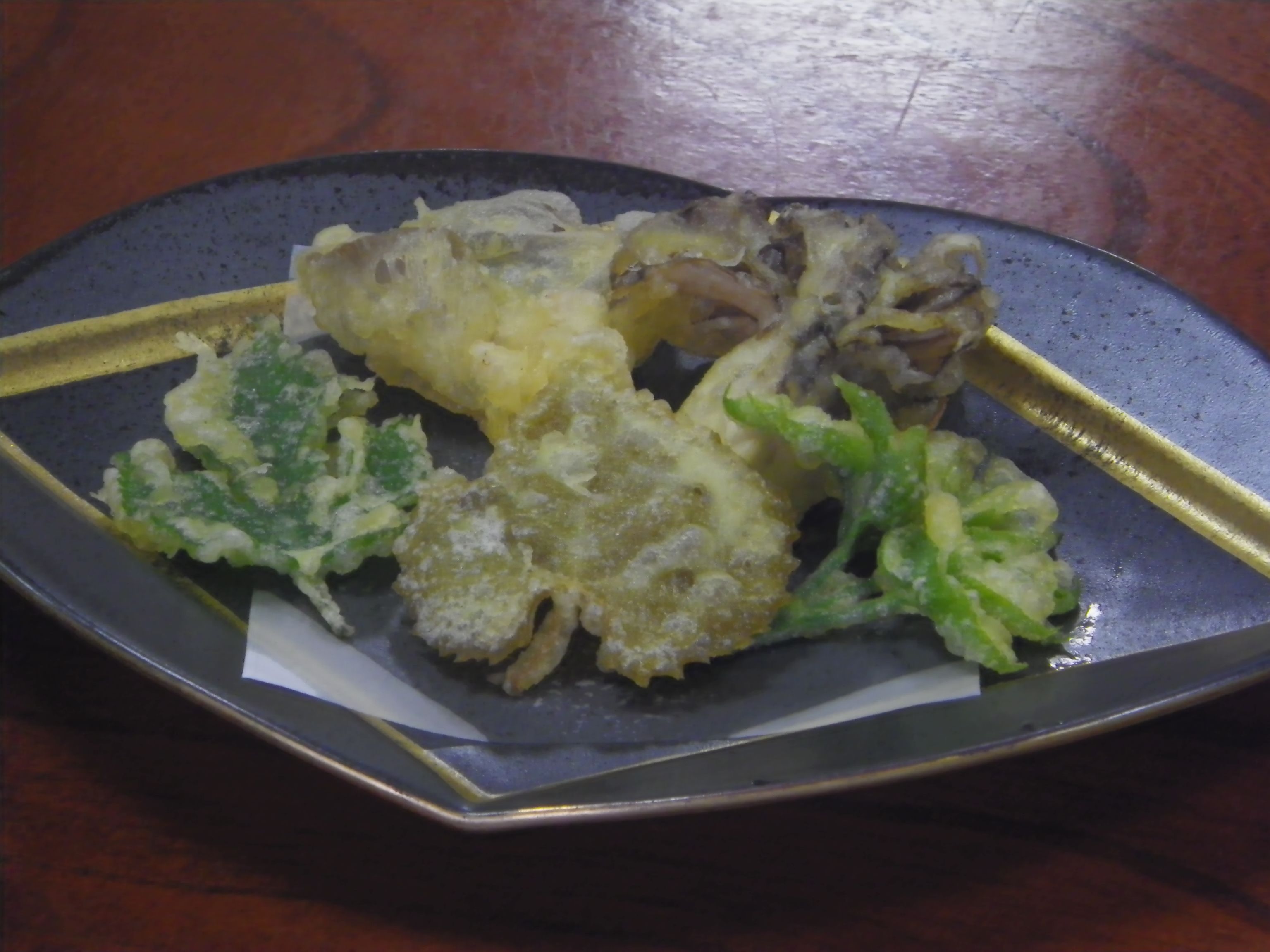 A plate of food with various items including what appears to be fried vegetables and possibly some meat.