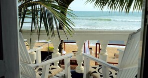 A beach view from a porch with white railings and a palm tree. - Neptune Story Hotel (Weligama)