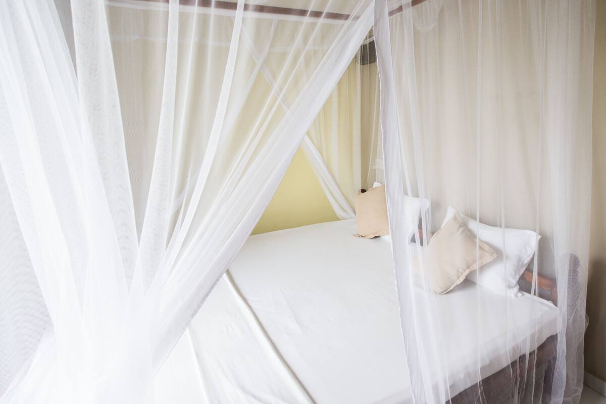 A bed with white bedding and a canopy.