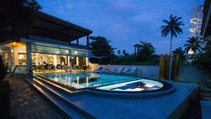 A pool area with lounge chairs and a building with a covered seating area. - Neptune Story Hotel (Weligama)