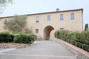 A building with a central arched entrance, surrounded by greenery and a gravel path leading to it. - La Senesina, Monteriggioni, Siena. In the best countryside of Tuscany ! (Siena)