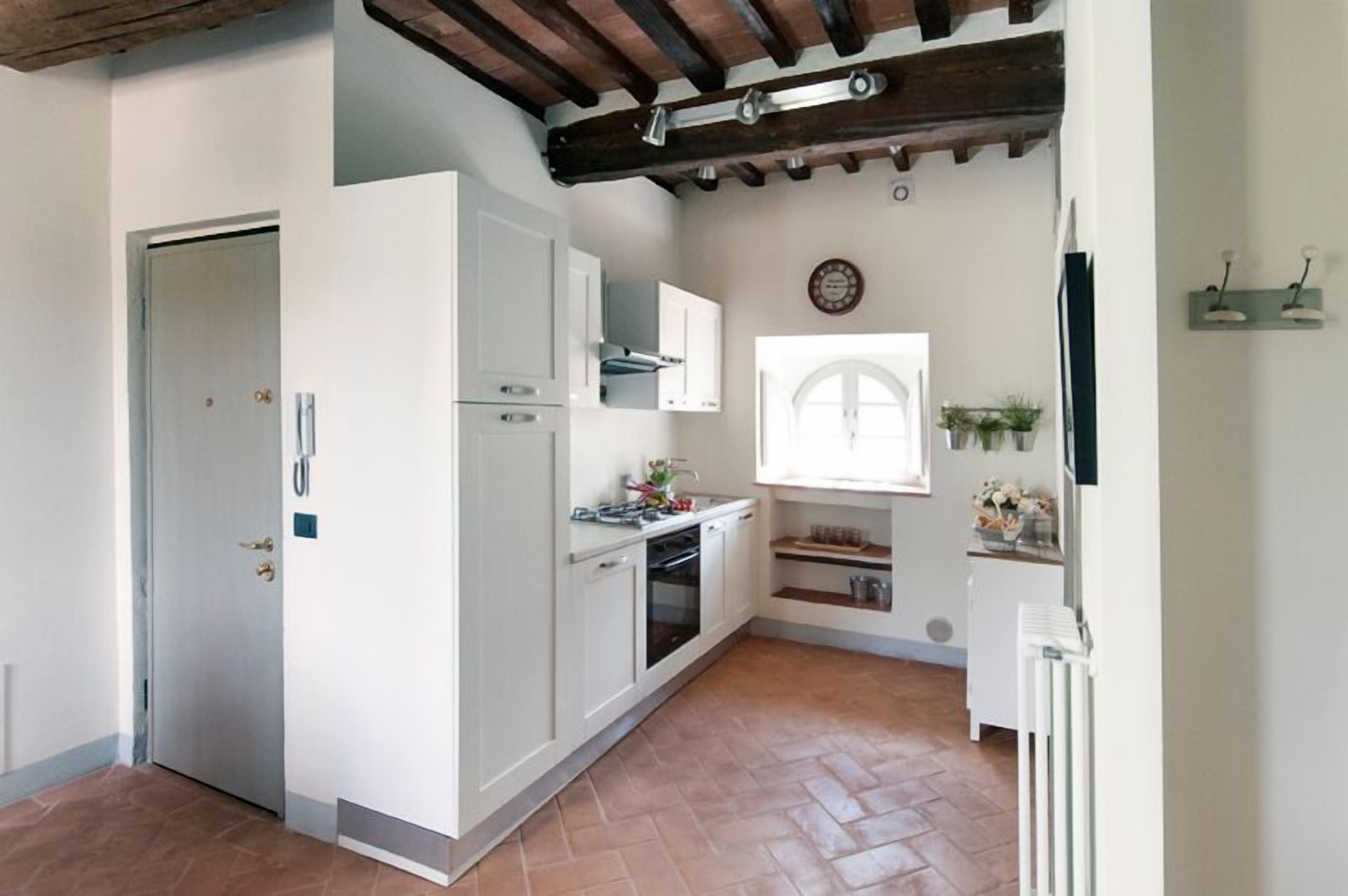 Une cuisine compacte avec des meubles blancs, un four encastré et une fenêtre offrant une belle vue.