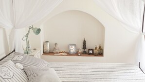 Ein Schlafzimmer mit Himmelbett, Nachttisch mit Lampe und einer Regal mit Dekoration.