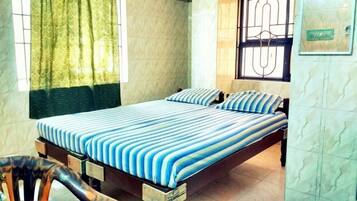 A room with a bed, a chair, and a window with curtains.