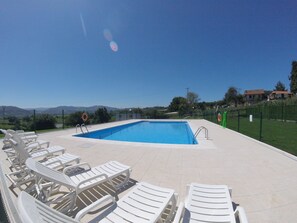 Une piscine avec des chaises longues, une bouée de sauvetage et une vue sur la campagne.