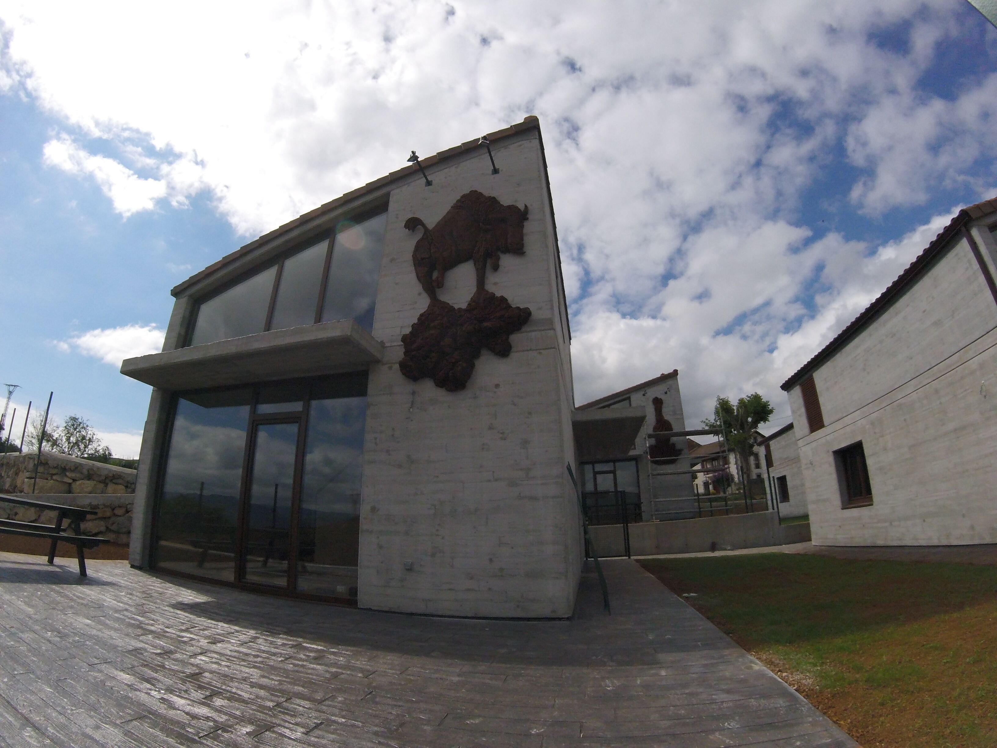 A modern building with a large stone lion sculpture on the facade, large windows, and a paved walkway.