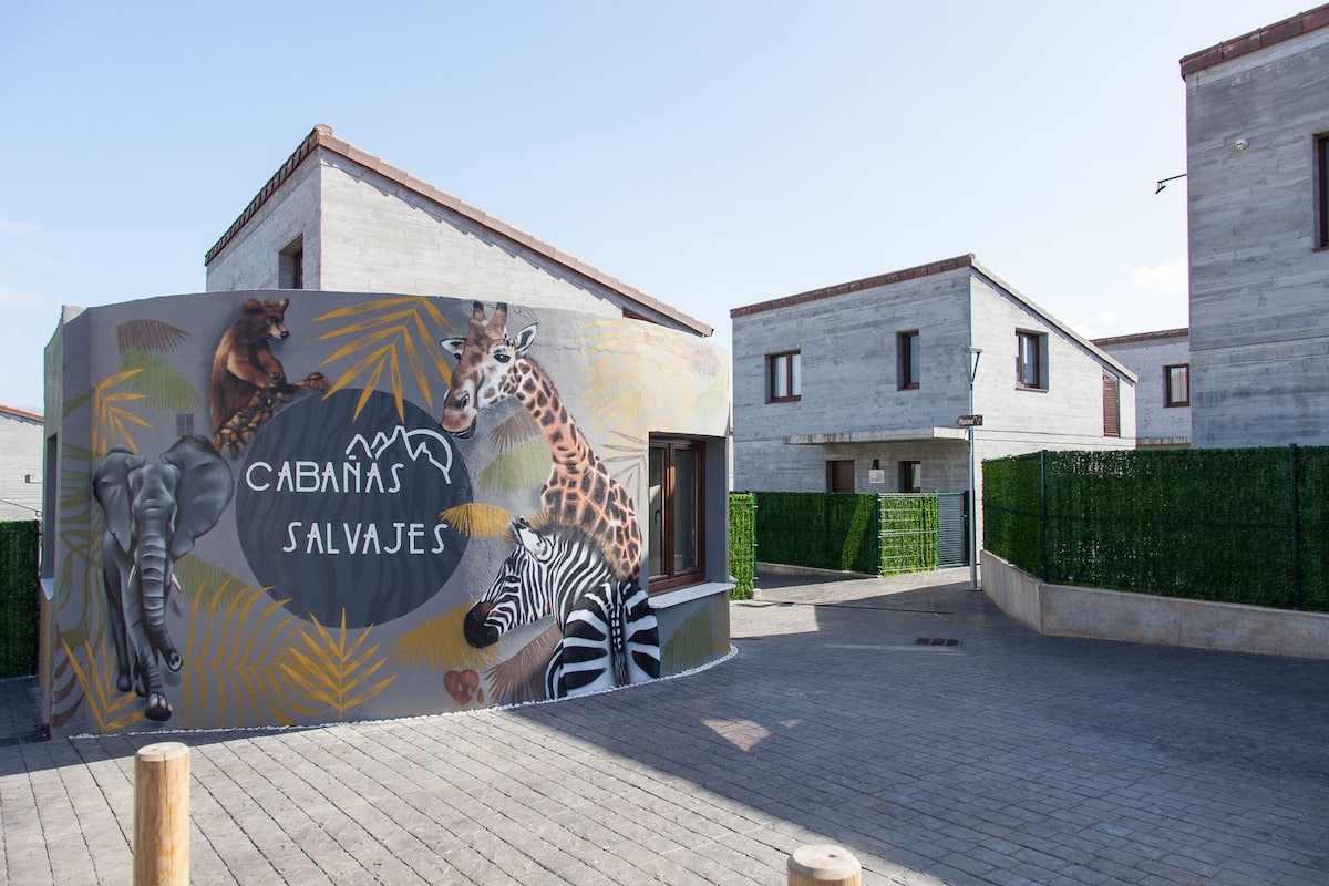 Een gebouw met een muurschildering van dieren en de tekst 'CABANAS SALVAJES'.