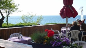 Un espace extérieur aménagé avec des tables et des chaises, offrant une vue sur une étendue d’eau.