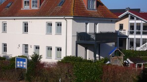 Un immeuble à plusieurs étages, doté d’une façade blanche, de nombreuses fenêtres et d’un balcon.