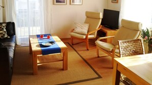 Un salon comprenant un canapé, deux fauteuils, une table basse et un téléviseur.