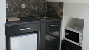 A compact kitchen with a built-in refrigerator, a microwave, and a sink. - Lisbon Beach Apartments 6. Studio, beach 5 minutes,  free wifi. (Costa da Caparica)