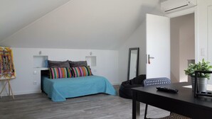 A bedroom with a bed, a desk, a chair, an air conditioner, and a potted plant. - Lisbon Beach Apartments 6. Studio, beach 5 minutes,  free wifi. (Costa da Caparica)