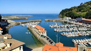 A marina with boats docked, a stone wall, and buildings with red roofs. - Quiet apartment in the geographical center of the Basque Country (Mendaro)