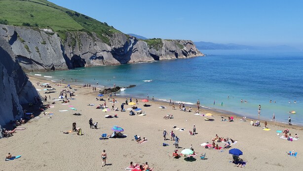 A beach with people sunbathing and swimming, cliffs in the background, and a clear sky. - Quiet apartment in the geographical center of the Basque Country (Mendaro)