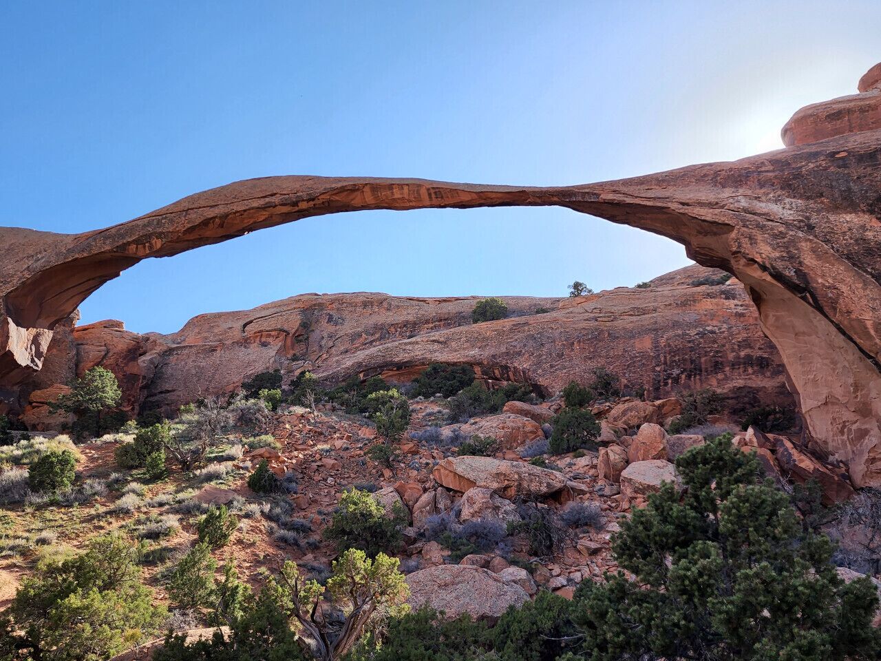 Une arche naturelle formée par la roche, entourée de végétation.