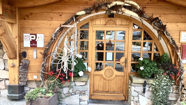 Un bâtiment en bois doté d’une grande entrée en arc de cercle, d’un mur en pierre et d’une porte en bois.