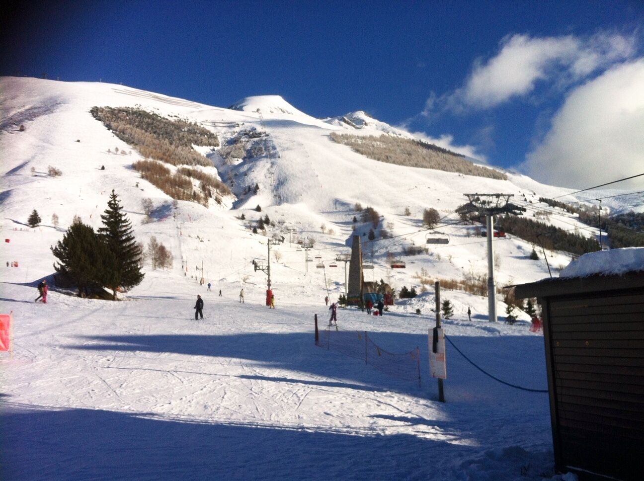 A snowy ski slope with a ski lift, trees, and a mountain in the background.