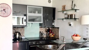 Une cuisine moderne avec des meubles de couleur sombre, un four à micro-ondes, un évier et un îlot central en verre.