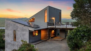 A modern two-story house with a balcony, large windows, and a view of the landscape. - A Sanctuary to Relax and Refresh all your Senses (Inverness)