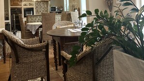 A dining area with wicker chairs, a wooden table, and a hanging light fixture.