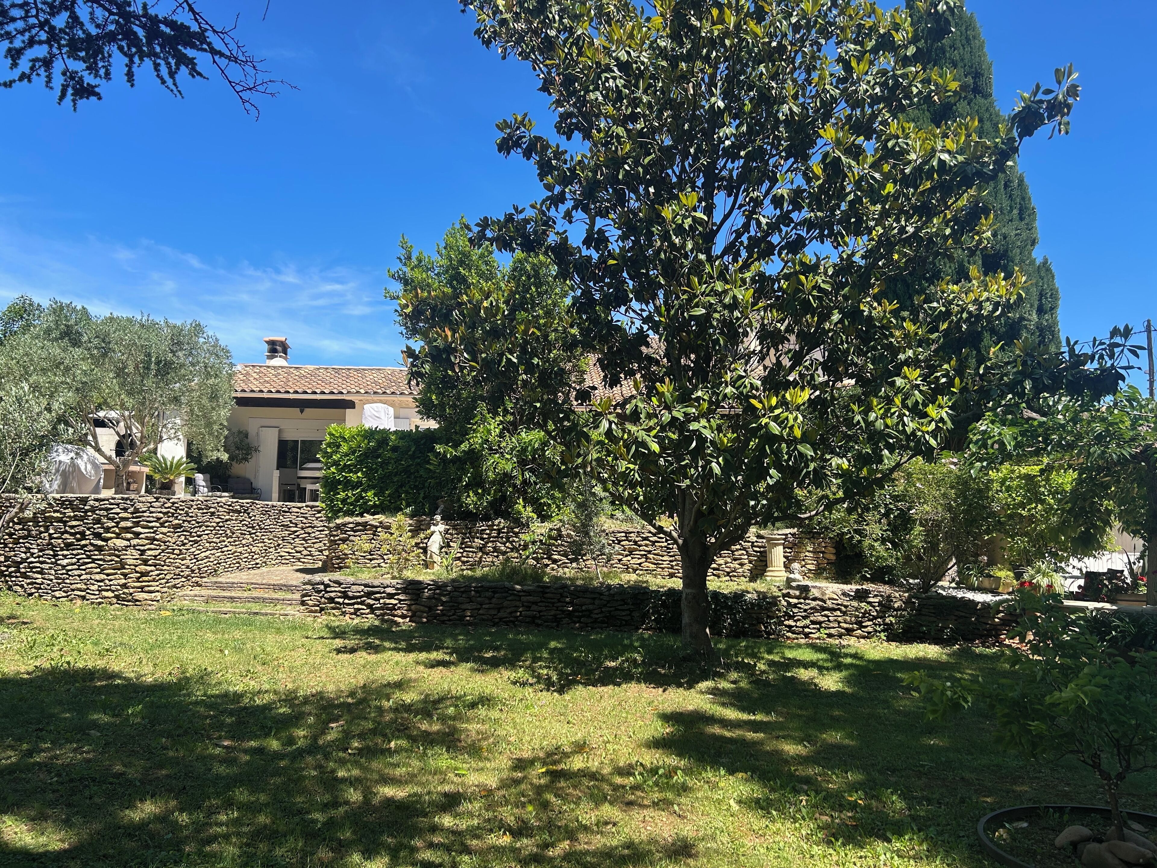 A stone wall, a tree, and a building with a tiled roof.