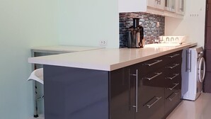 A modern kitchen with a central island, white cabinets, a black backsplash, and a washing machine. - Super-clean Penthouse (WIFI) - Luxury Pad with everything for the vacation (Koh Samui)