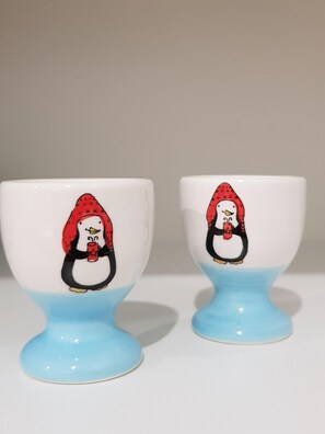 Two ceramic cups with penguin illustrations.