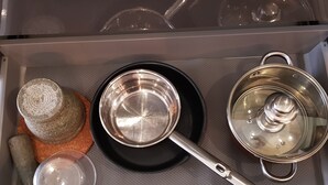 A kitchen drawer with a black pot, a stainless steel pot, a glass measuring cup, and a wooden rolling pin. - Super-clean Penthouse (WIFI) - Luxury Pad with everything for the vacation (Koh Samui)