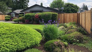 A residential property with a well-maintained garden, a wooden fence, and a satellite dish on the roof.