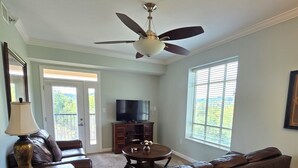 A living room with a ceiling fan, a TV, a sofa, a coffee table, and a lamp. - Luxury Condo! 4 Miles To Dollywood, Easy Walk To Shops & Restaurants (Pigeon Forge)