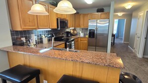 A modern kitchen with wooden cabinets, stainless steel appliances, and a granite countertop. - Luxury Condo! 4 Miles To Dollywood, Easy Walk To Shops & Restaurants (Pigeon Forge)