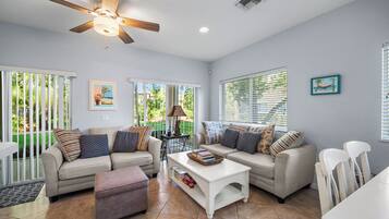 A spacious living room with two sofas, a coffee table, and a ceiling fan.