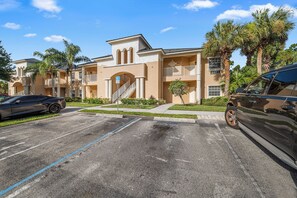 A multi-story building with a parking lot, a wheelchair accessibility sign, and a palm tree. - PGA Village/Castle Pines Best Location Pet Friendly. (Port St. Lucie)