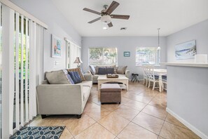 Una sala de estar con sofá, reposapiés y una zona de comedor con sillas y mesa.