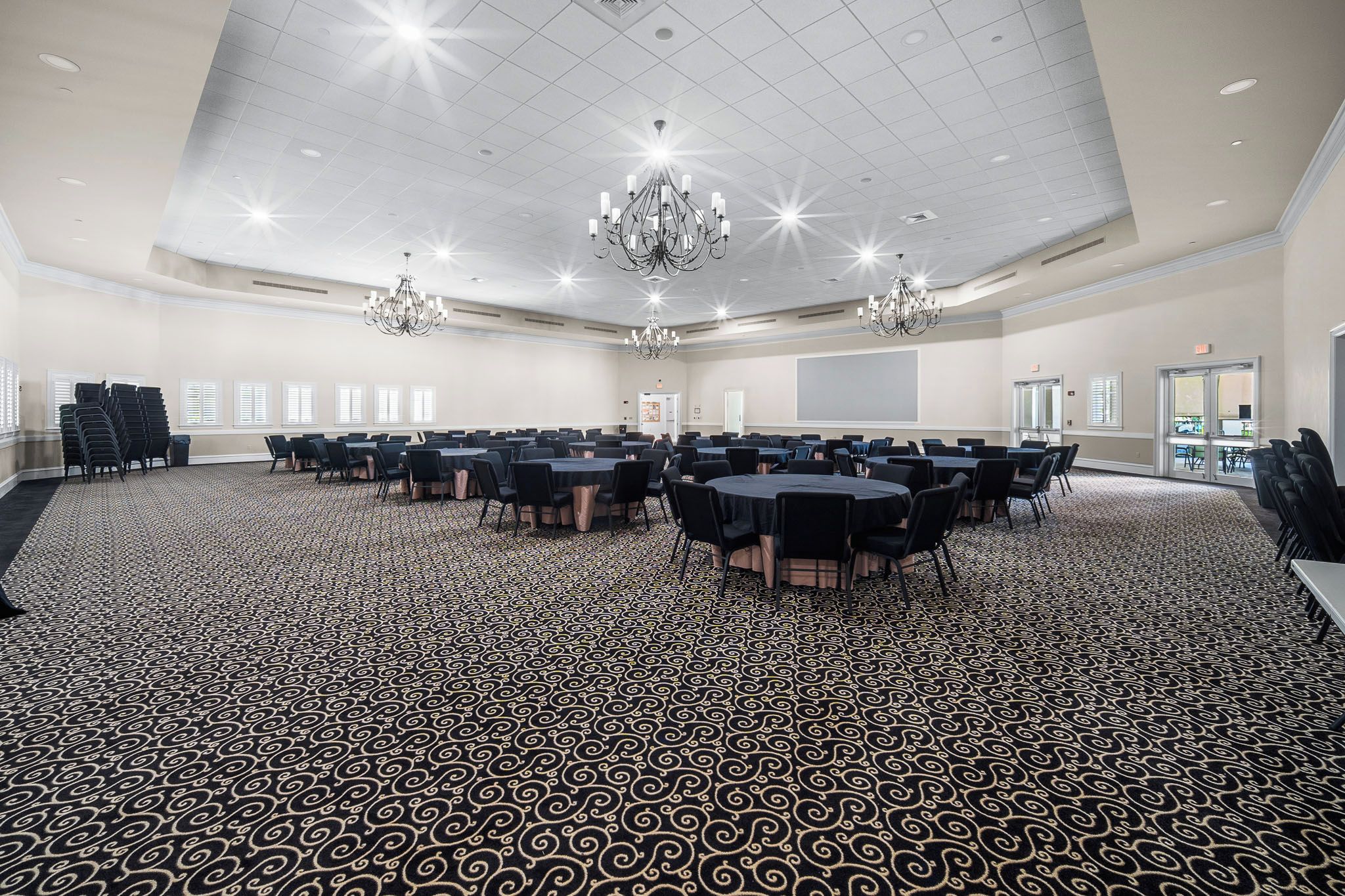 A conference room with a patterned carpet, multiple tables, chairs, and chandeliers.