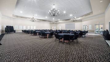 A conference room with a patterned carpet, multiple tables, chairs, and chandeliers.