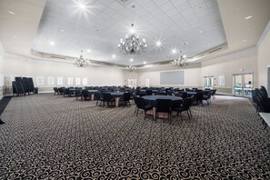 A conference room with a patterned carpet, multiple tables, chairs, and chandeliers.