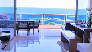 Un grand balcon offrant une vue sur l’océan, aménagé avec des tables et des chaises.