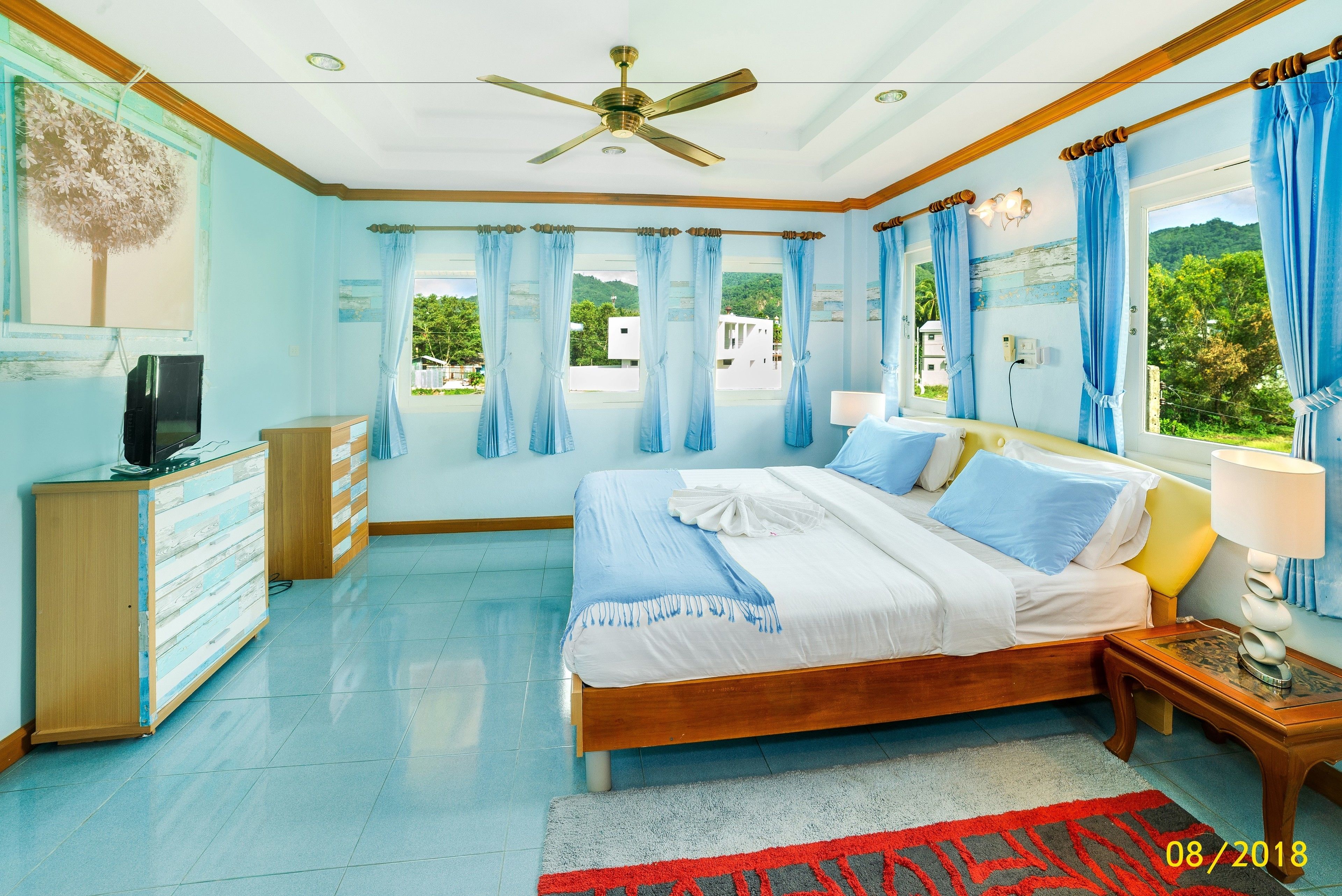 A bedroom with a bed, a ceiling fan, a TV, and a dresser.