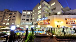 A hotel with multiple floors, outdoor pool area, and a well-lit entrance. - Aquarius resort (Geoje)